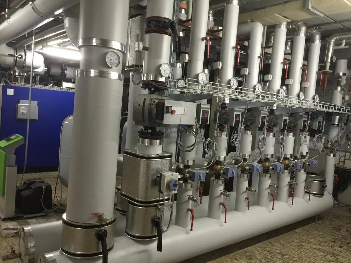 Isolierter Heizungsverteiler mit Pumpen und Armaturen im Technikraum